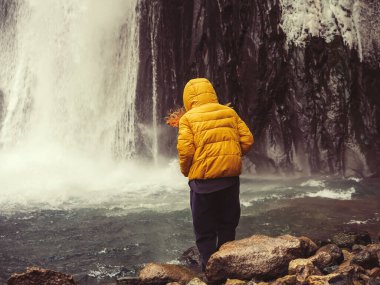 Rüzgârla savrulan bir kadın bir dağ nehrine adım atar ve şelalenin güçlü, buzlu bir nehrine akar..