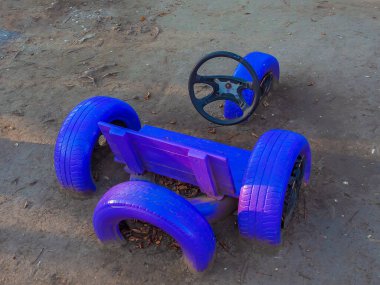 Direksiyona takılı direksiyonlu ahşap ve araba tekerleklerinden yapılmış mavi bir bank. Dambıl şeklinde bir benç. Sahada alışılmadık bir koltuk.