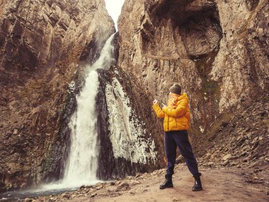 Bir kadın parmaklarını Kafkasya 'nın sarp kayalıklarından akan buz gibi ve güçlü bir şelaleye doğrultur.