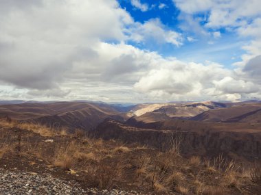 Kafkasya 'nın dağ sıralarının bulunduğu vadi, bulutların arasından bakan mavi gökyüzünün arka planına karşı.
