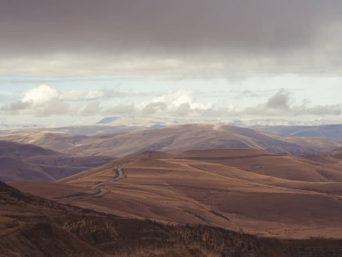Serpentine yolu, bulutların altında görünen bir platoyla Kafkasya 'nın dağlık tepelerinden geçiyor. Yükseklerden görünüm