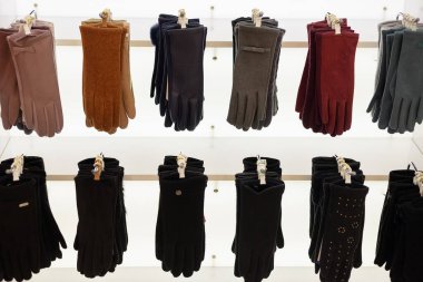 Farklı malzemelerden ve farklı renklerden yapılmış kadın eldivenleri bir mağazada asılı duruyor.