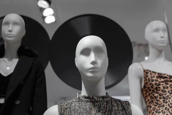 White female mannequin in a fashion store against the backdrop of decor from vinyl records