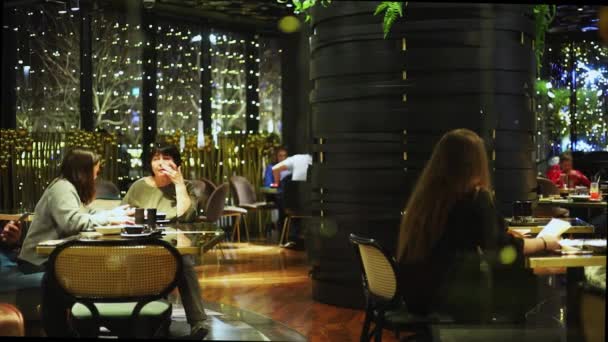 Rusland, Krasnodar 07.01.2022. Besøgende chatte over en kop kaffe og spise i den romantiske atmosfære af en aften cafe – Stock-video