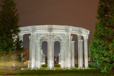 Rusya, Krasnodar 07.01.2022. Parlak bir sütun, gece parkındaki haydutlar arasındaki yeşil çimenleri süslüyor.