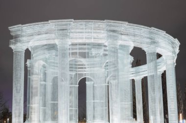 Rusya, Krasnodar 07.01.2022. Bulutlu bir gece gökyüzünün altındaki bir parka yarı dairesel aydınlık çerçeve sütunları monte edilir. Yakın plan fotoğraf.