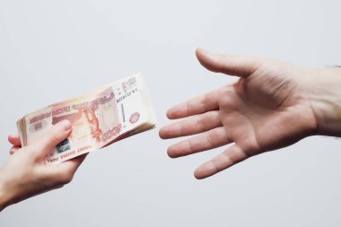 Bir kadının eli, bir erkeğin eline beş bin dolarlık banknot uzatır.