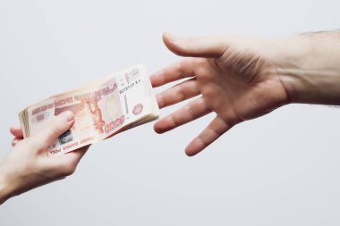 Bir erkeğin avuç içi, bir kadının elinde duran beş bin dolarlık banknota uzanır..