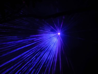 Parlak bir spot ışığı, gece karanlığında neon mavi ışınlar yansıtıyor. Lazer gösterisi.