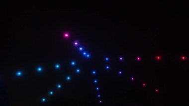 Gece karanlığında hareket eden yıldızın şeklini tasvir eden parlak renkli ışıklar. İHA gösterisi.