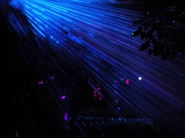 Parlak neon ışınları, parlak parlak ışıklarla karanlık uzayı aydınlatır. Lazer gösterisi. Uzun pozlama. Bulanık resim