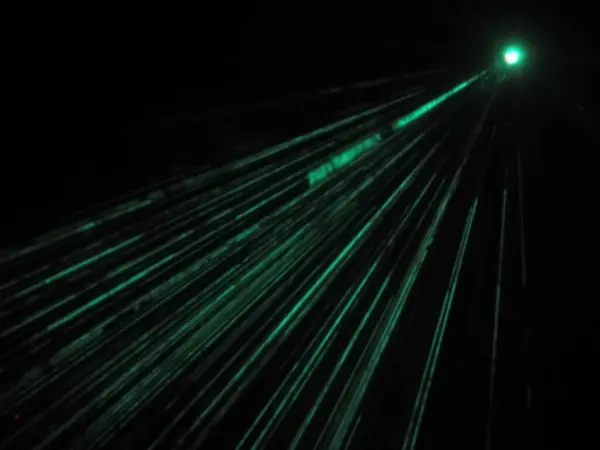 The outdoor projector shines bright emerald beams in dark. Laser show. Blurred image