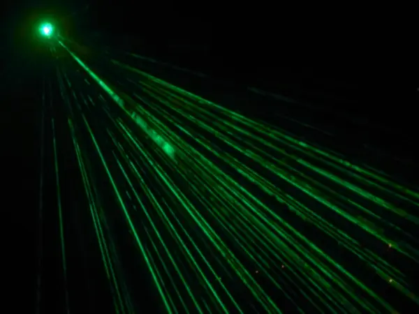 Outdoor projector shines bright green beams in dark. Laser show. Blurred image