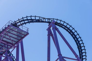 Bulutsuz mavi gökyüzüne karşı mavi-mor lunapark treninin bir parçası. Aşırı cazibe. Metal yapı.