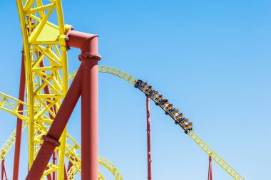 Tramvaydaki insanlar mavi gökyüzüne karşı lunapark trenine biniyorlar. Eğlence parkında aşırı eğlence..