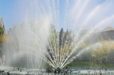 Eğlence parkındaki bir çeşme güneşli bahar gününde her yöne su püskürtür.