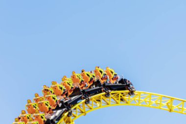 Turuncu koltuklu bir tramvay mavi gökyüzüne karşı sarı hız trenini hızlandırır. Lunaparktaki aşırı cazibe. Bulanık resim