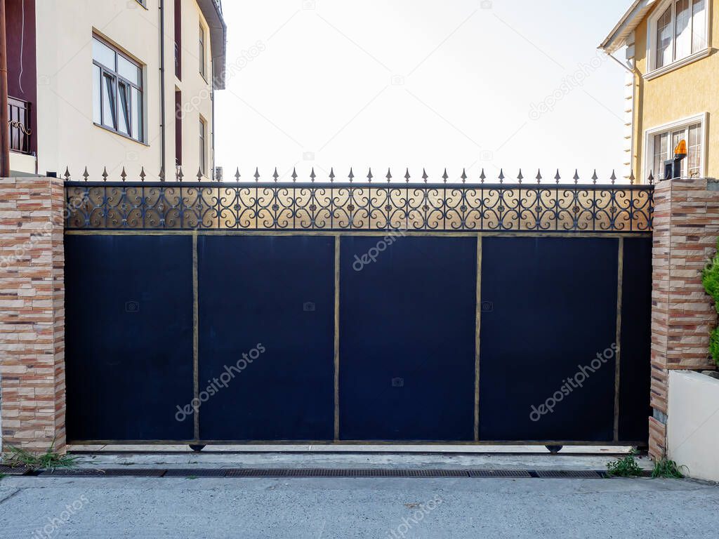Iron black sliding gates with patterned forged edging enclose the private area.
