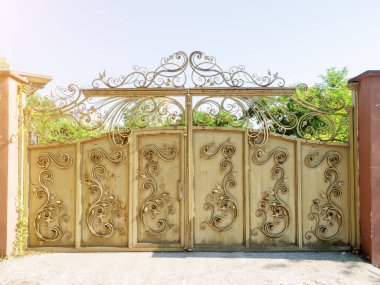 Yazın güneşli bir günde işlenmiş demir desenli ve pas lekeli bej bir demir kapı. Terk edilmiş özel bölge