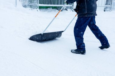 Temizlikçi kar kürüyor. Kışın kar temizleme yağışı