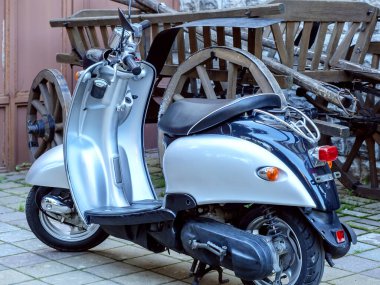 Yepyeni gümüş bir motosiklet eski bir ahşap arabanın yanına park edilmiş.