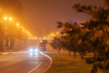 Pırıl pırıl farları olan bir araba sisli bir gece yolunda gidiyor. Bulanık resim