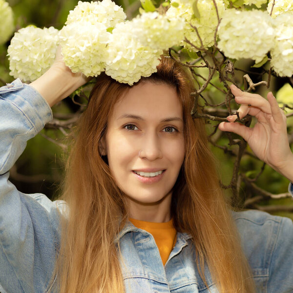 A woman in viburnum buldenezh flowers. Viburnum buldenezh. Selective focus.