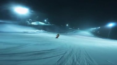 Gece kayak pistinde kayak yapmak. Kar yağarken çekilen gece. Hareket halindeyken ateş ediyorlar..