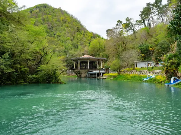 Nehrin kıyısında bir çardak. Yeşil bir parkta sakin geniş bir turkuaz nehri.