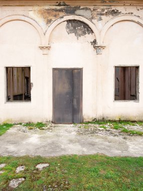 Demir kapısı ve kırık camları olan terk edilmiş eski bir bina.