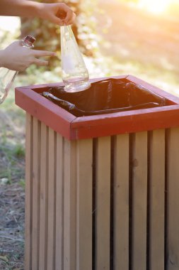 Elinde bir kova olan iki boş cam şişenin ellerinde. Konteynır camının atılması