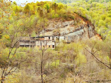 Kayalık ormanlık alanda terk edilmiş bir bina. Kayalık tepeler bahar yaprak döken ormanlarla kaplandı.