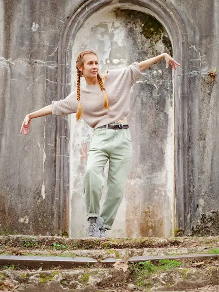 A woman performs modern dances in an old abandoned architecture