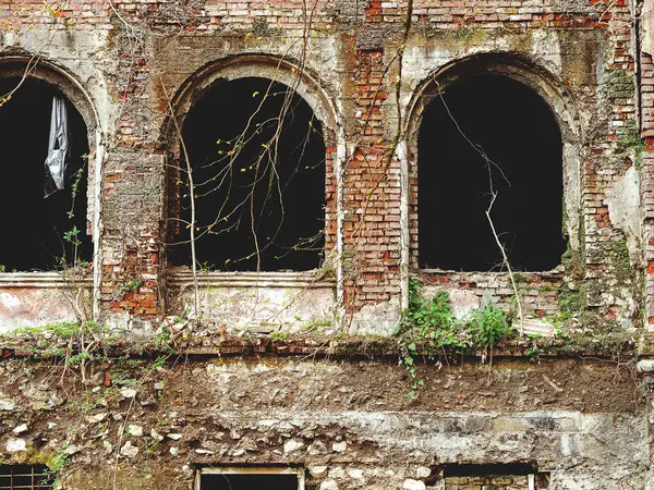 Abandoned building with arched windows. Arched window openings without glass. House with ghosts.