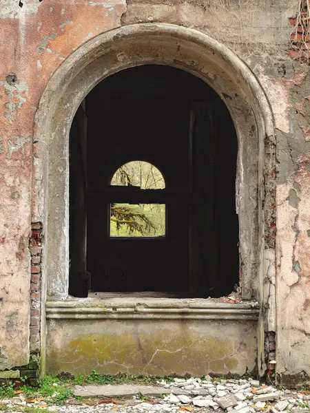 Arched window opening of a tattered abandoned building.