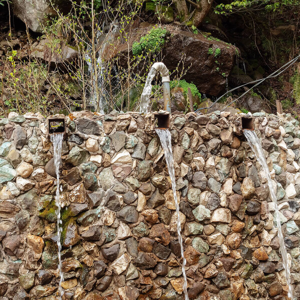 Water flows from a pipe along a stone wall