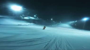 Gece kayak pistinde kayak yapmak. Kar yağarken çekilen gece. Hareket halindeyken ateş ediyorlar..