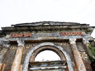 Bulutlu bir gökyüzüne karşı kemerli penceresi olan terk edilmiş bir tren istasyonu.