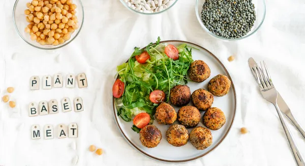 Top view Vegan veggie meatballs on the plate with fresh salad. Pea protein ingredients on the background. Plant based meat concept.Vegetarian lunch. Healthy eating. Go vegan. Wide banner.