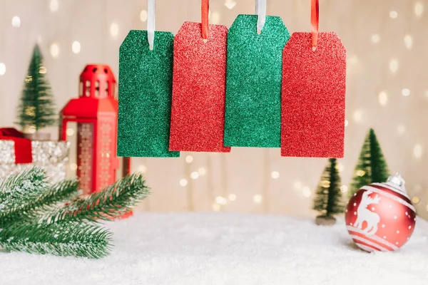四个带有复制空间的礼物标签或标签，用于与冷杉树枝、红球装饰、雪灯在温暖的灯光背景下的圣诞作文的文字复制。有选择的重点. — 图库照片