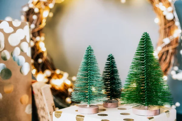 Pequeños árboles de Navidad decorativos en las cajas de regalo con corona iluminada sobre fondo de pared gris. Decoración festiva para el hogar. Feliz Navidad y Año Nuevo. Tarjeta postal con espacio de copia para escribir texto. — Foto de Stock