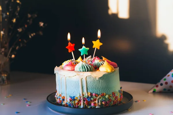 Красочный праздничный торт с брызгами и горящими свечами в форме звезды на темном фоне стены с тенями. Праздничный день рождения, вечеринка. Выборочный фокус, копировальное пространство — стоковое фото