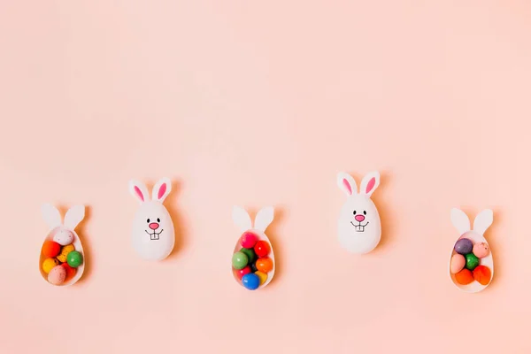 Paskalya bayramı için bej şeftali rengi arka planda çikolatalı yumurtalarla dolu komik tavşan yumurtaları kutuları var. Tavşan sembolü. Paskalya yumurtası avı. Yaratıcı Paskalya. Düz yatıyordu. Boşluğu kopyala. — Stok fotoğraf