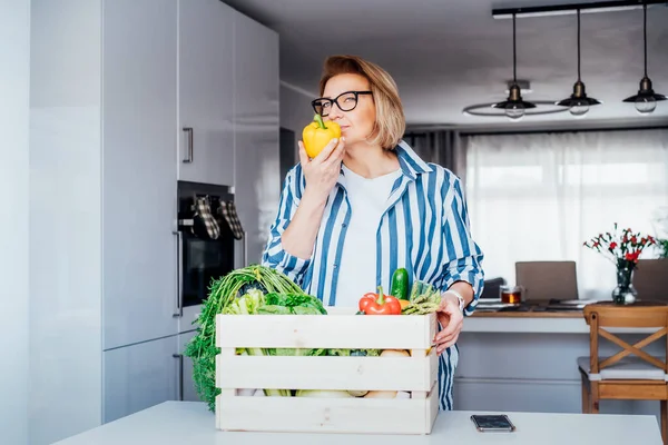 Woman checking fresh organic bell pepper from a wooden box with fresh vegetables. Local farmer healthy food. New Start of a healthy life, weight loss concept. Online home food delivery. Copy space — Stock Photo, Image