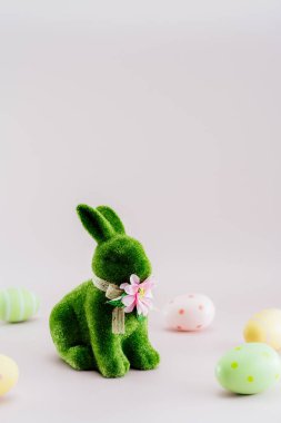 Yeşil tavşan heykelciği ve renkli paskalya yumurtaları tarafsız pembe arka planda farklı şekillerde. Bayramlık Ester bahar dikey kart modeli. Seçici odaklanma. Boşluğu kopyala.