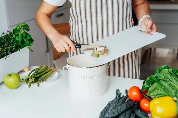 Compost the kitchen waste, recycling. Household woman scraping, throwing vegetables cutting leftovers into the garbage, compost bin while cooking on her kitchen. Environmentally responsible, ecology — Stock Photo, Image
