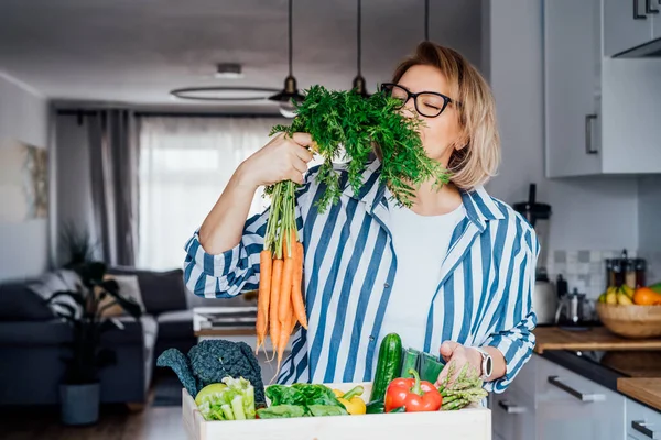 Woman checking fresh organic carrots from a wooden box with fresh vegetables. Local farmer healthy food. New Start of a healthy life, weight loss concept. Online home food delivery. Copy space. — Stock Photo, Image