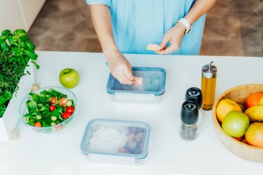 Kilo vermek için sağlıklı bir diyet planı, günlük hazır yemek menüsü. Yakından bir kadın beslenme çantasına önceden pişirilmiş, akşam yemeği için hazır bir not bırakıyor. Sağlıklı yemekle dengeli porsiyon. Pişirme öncesi konsept.