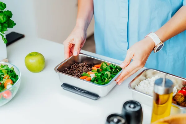 Healthy diet plan for weight loss, daily ready meal menu. Close up Woman weighing lunch box cooked in advance,ready to eat on kitchen scale. Balanced portion with healthy dish. Pre-cooking concept — Stock Photo, Image