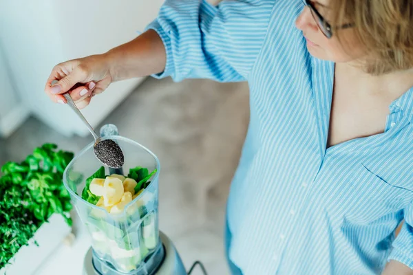 Fermer femme ajoutant des graines de chia lors de la fabrication de smoothie dans la cuisine. Complément alimentaire. Alimentation végétalienne saine de désintoxication. Une alimentation saine programme de perte de poids. Concentration sélective. Espace de copie. — Photo